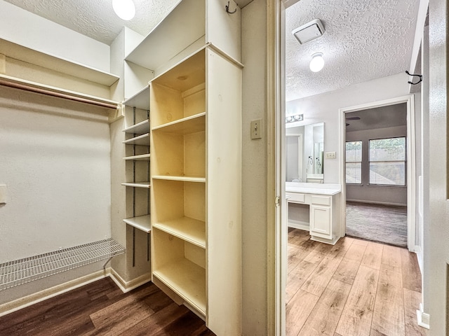 spacious closet with light hardwood / wood-style floors and built in desk