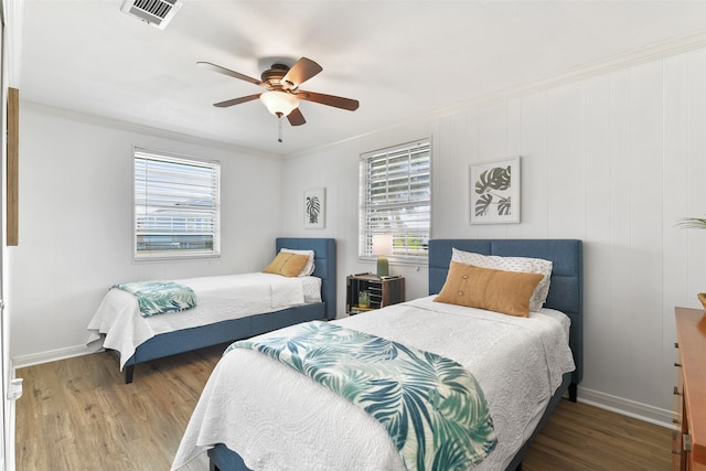 bedroom with ceiling fan, multiple windows, crown molding, and wood-type flooring