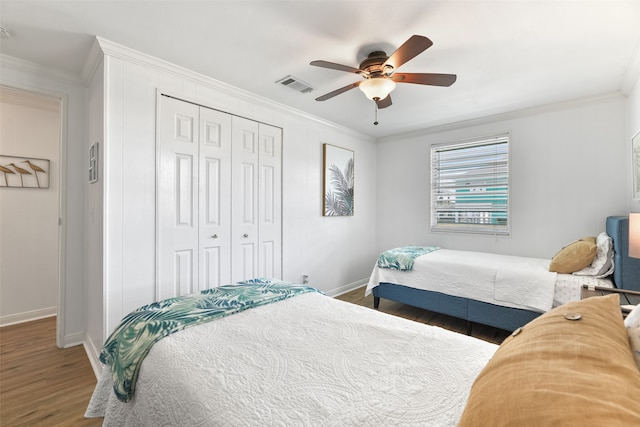 bedroom featuring dark hardwood / wood-style flooring, a closet, ornamental molding, and ceiling fan