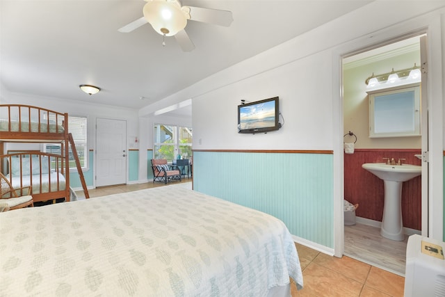 bedroom with sink, light tile patterned floors, ceiling fan, and ensuite bathroom