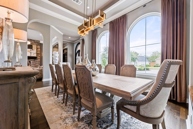 dining room featuring a healthy amount of sunlight, dark hardwood / wood-style floors, and ornamental molding