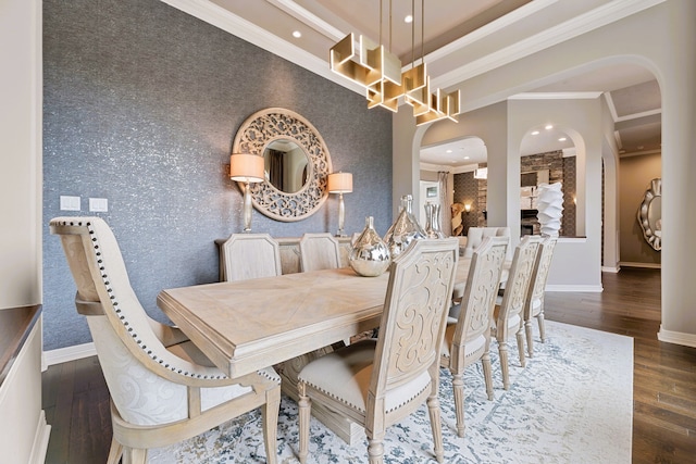 dining area with dark hardwood / wood-style flooring, a large fireplace, and crown molding