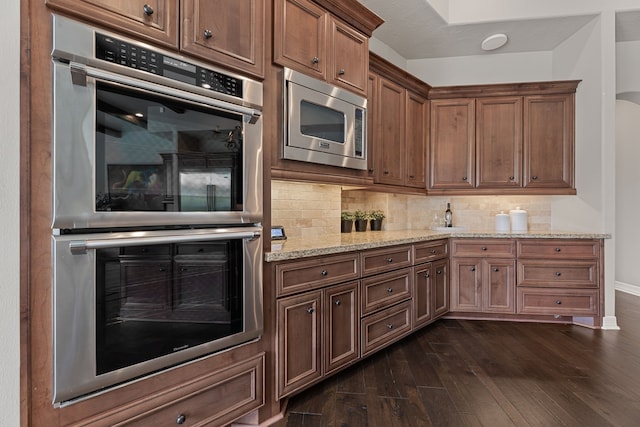 kitchen featuring decorative backsplash, dark wood-type flooring, light stone counters, and appliances with stainless steel finishes