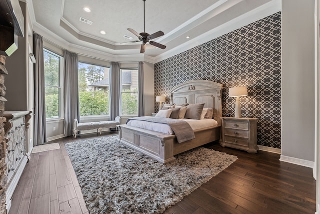 bedroom with a tray ceiling, ceiling fan, crown molding, and dark wood-type flooring