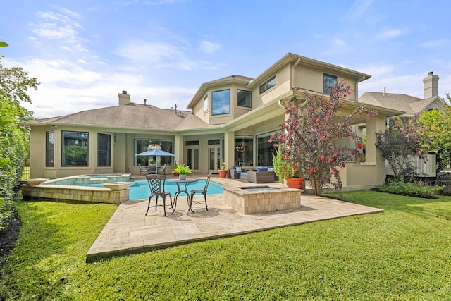 back of house with an in ground hot tub, a patio, and a lawn