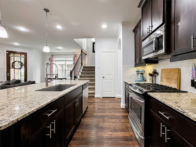 kitchen with ornamental molding, appliances with stainless steel finishes, hanging light fixtures, sink, and dark wood-type flooring