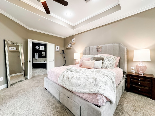 carpeted bedroom featuring ensuite bath, a raised ceiling, ceiling fan, and crown molding