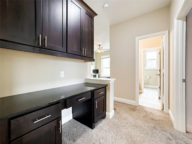 kitchen with built in desk, dark brown cabinets, a healthy amount of sunlight, and light carpet