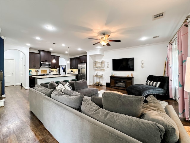 living room featuring ornamental molding, plenty of natural light, ceiling fan, and dark hardwood / wood-style floors