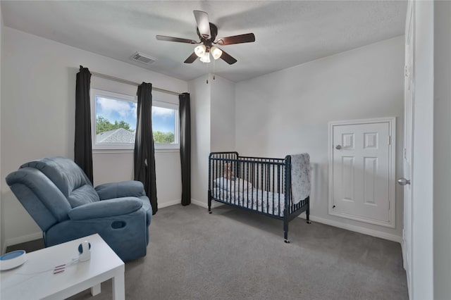 carpeted bedroom with ceiling fan and a nursery area