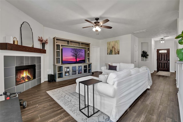 living room featuring ceiling fan, a tile fireplace, and dark hardwood / wood-style floors