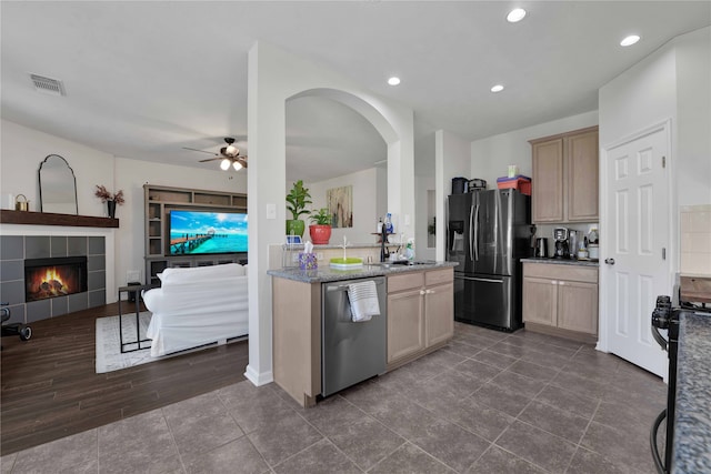 kitchen featuring light brown cabinets, a fireplace, appliances with stainless steel finishes, and dark hardwood / wood-style floors