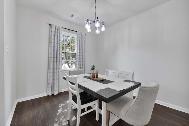 dining space featuring dark hardwood / wood-style floors and an inviting chandelier