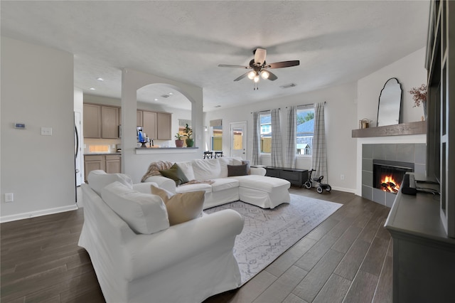 living room featuring a textured ceiling, a fireplace, dark hardwood / wood-style floors, and ceiling fan