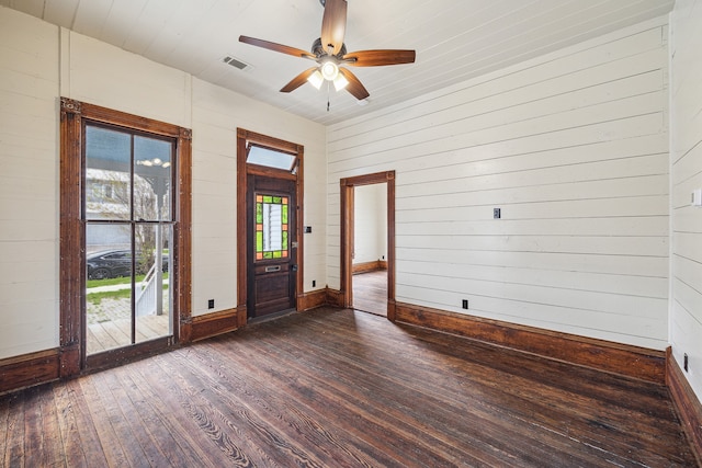 entrance foyer featuring dark wood-type flooring, ceiling fan, and wood walls