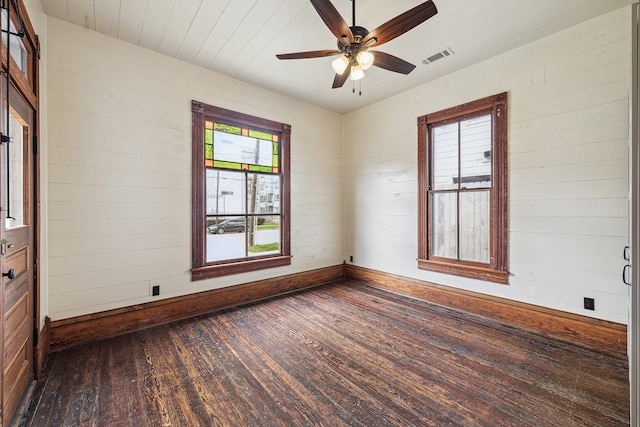 empty room with wood walls, ceiling fan, and dark hardwood / wood-style floors