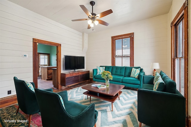 living room featuring wood walls, hardwood / wood-style flooring, and ceiling fan