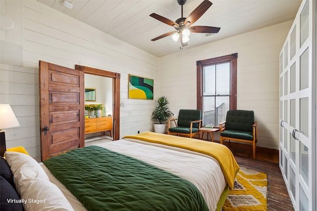 bedroom featuring dark hardwood / wood-style flooring, wood walls, and ceiling fan