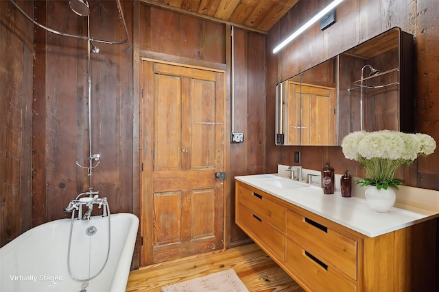 bathroom with wood-type flooring, a washtub, wood walls, wooden ceiling, and vanity