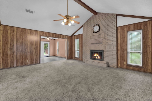 unfurnished living room featuring carpet floors, wooden walls, vaulted ceiling with beams, and a brick fireplace