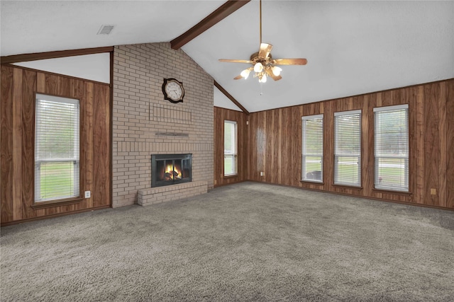 unfurnished living room featuring carpet flooring, a wealth of natural light, and wooden walls