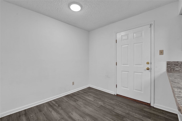 unfurnished room with dark wood-type flooring and a textured ceiling