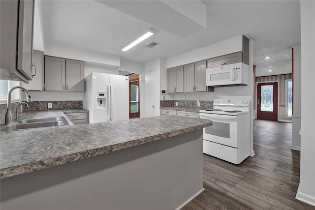 kitchen featuring dark hardwood / wood-style flooring, kitchen peninsula, a textured ceiling, sink, and white appliances