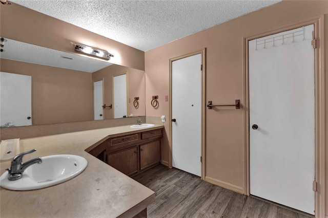 bathroom with a textured ceiling, vanity, and hardwood / wood-style flooring