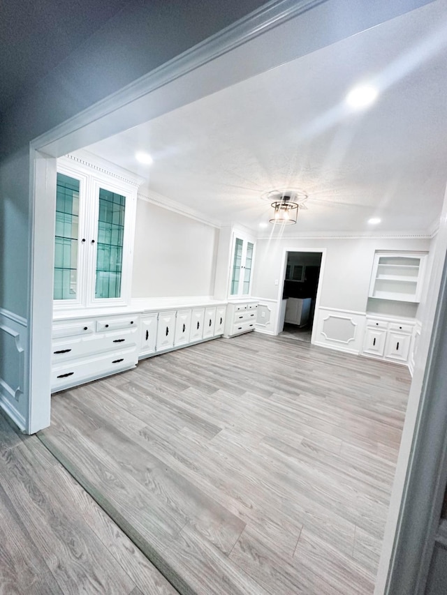 unfurnished living room with light wood-type flooring and crown molding