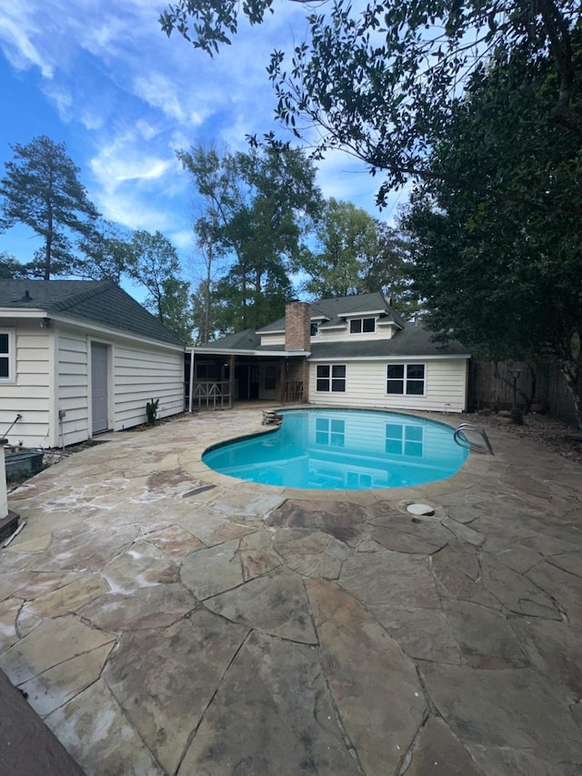 view of swimming pool with a sunroom and a patio area