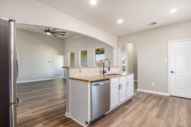 kitchen with white cabinetry, sink, light stone counters, appliances with stainless steel finishes, and light hardwood / wood-style flooring