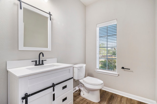 bathroom featuring hardwood / wood-style floors, vanity, a healthy amount of sunlight, and toilet