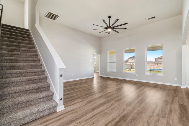 unfurnished living room featuring dark wood-type flooring, a high ceiling, and ceiling fan