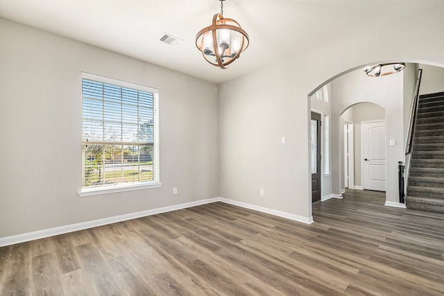 spare room featuring dark hardwood / wood-style floors and a chandelier