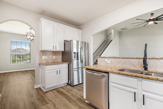 kitchen with sink, appliances with stainless steel finishes, tasteful backsplash, white cabinets, and light wood-type flooring