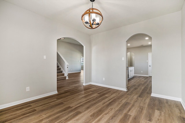 spare room with dark wood-type flooring and a chandelier