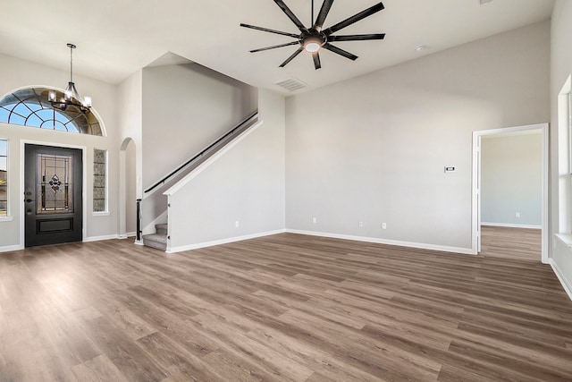 entrance foyer featuring a towering ceiling, ceiling fan with notable chandelier, and dark wood-type flooring