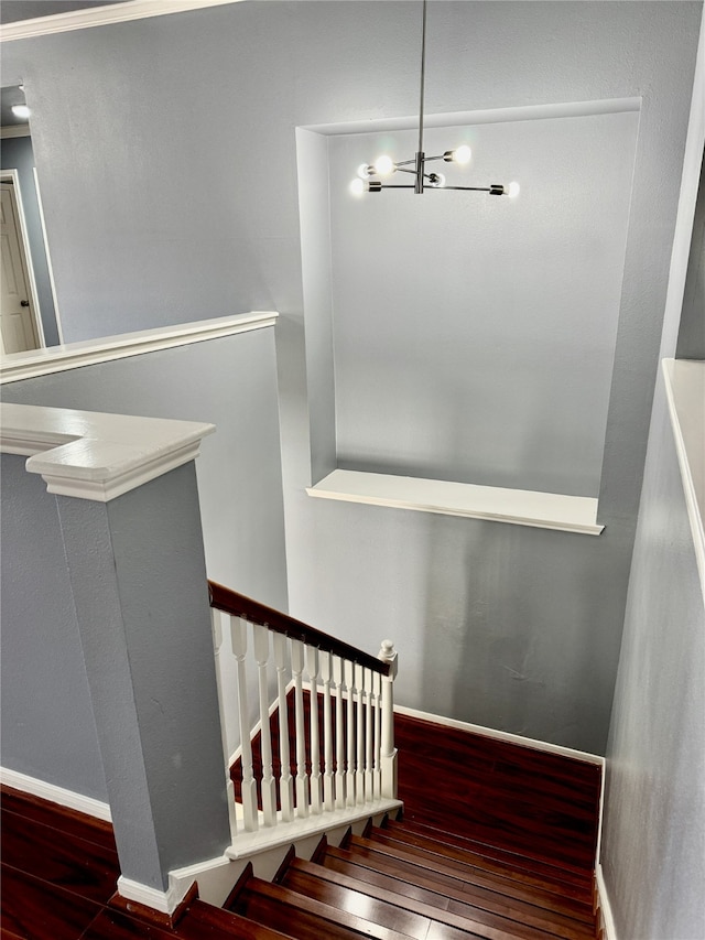 stairway with wood-type flooring and an inviting chandelier