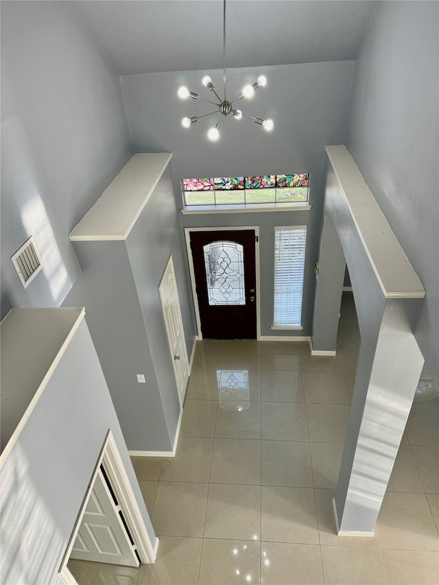 tiled foyer entrance with a high ceiling and a chandelier