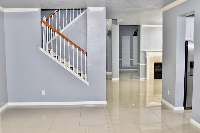 stairway featuring ornamental molding, a tiled fireplace, and tile patterned floors