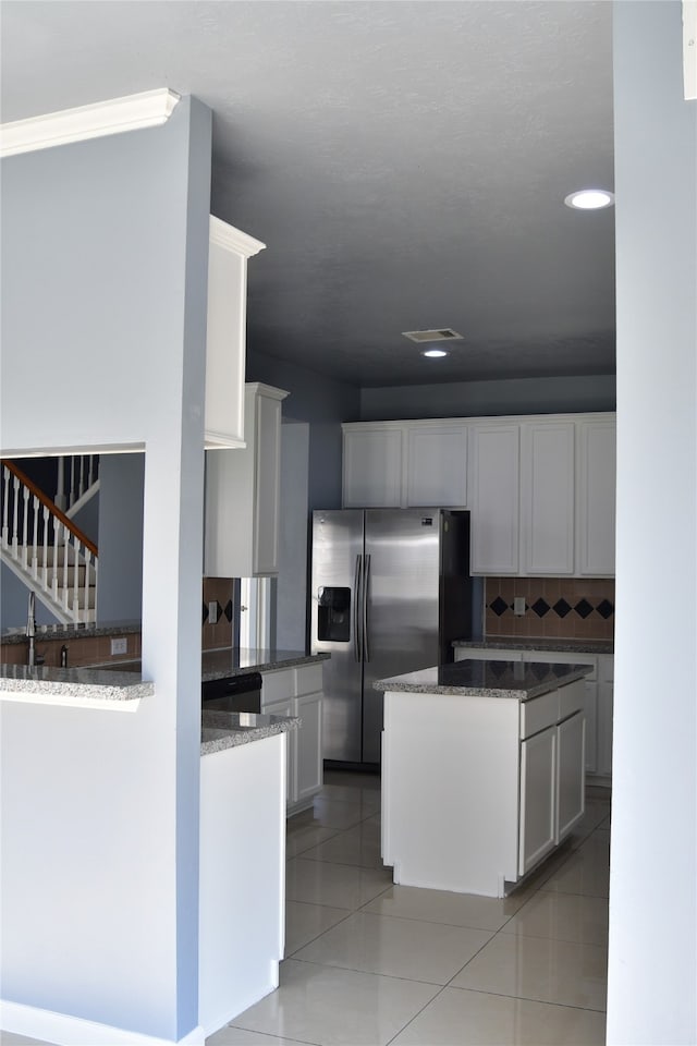 kitchen with tasteful backsplash, white cabinetry, appliances with stainless steel finishes, and light tile patterned floors