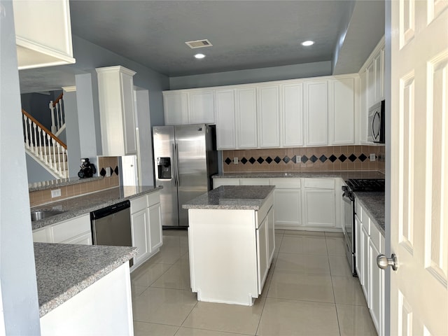 kitchen with backsplash, white cabinets, a kitchen island, and appliances with stainless steel finishes