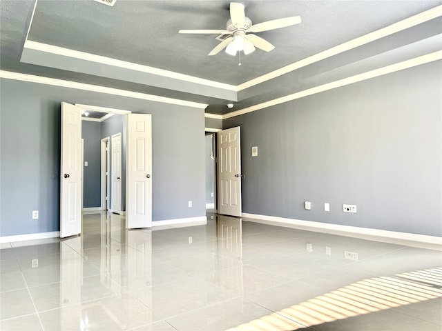 empty room featuring a tray ceiling, a textured ceiling, ceiling fan, and crown molding