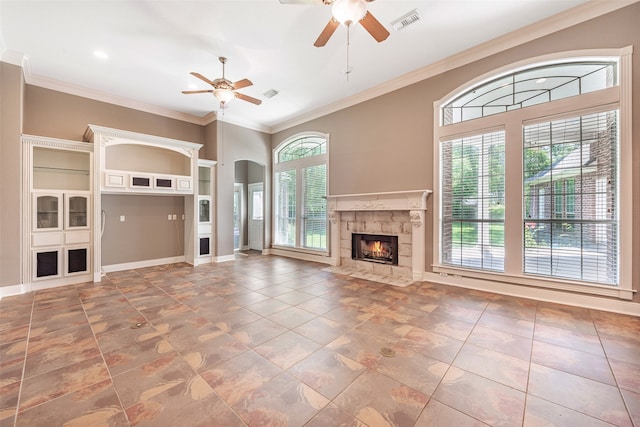 unfurnished living room with a wealth of natural light, a tiled fireplace, built in features, and crown molding