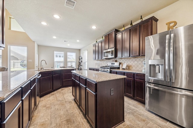 kitchen with sink, light hardwood / wood-style flooring, dark brown cabinets, a kitchen island, and stainless steel appliances