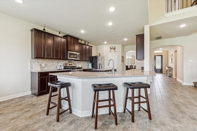 kitchen featuring a breakfast bar, light stone counters, sink, and stainless steel appliances