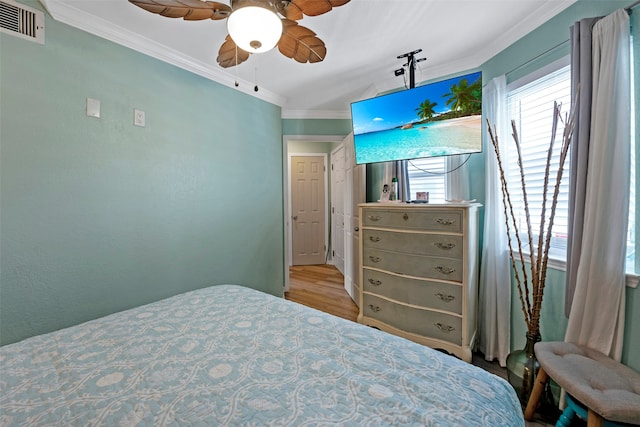 bedroom with ornamental molding, ceiling fan, and light hardwood / wood-style flooring