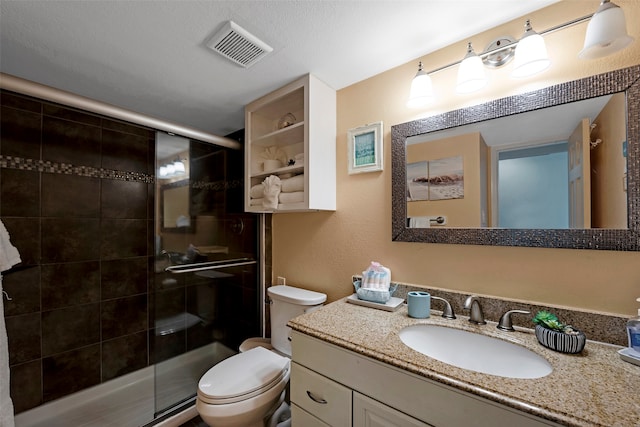 bathroom featuring vanity, a textured ceiling, toilet, and a shower with door