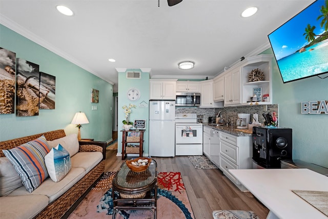 kitchen with white appliances, wood-type flooring, white cabinetry, and sink