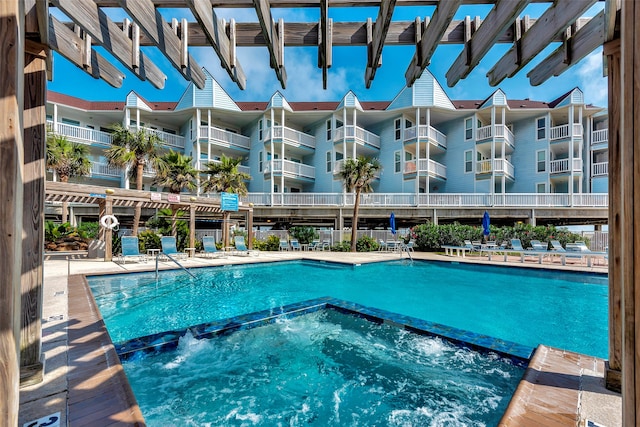 view of swimming pool with a hot tub, a pergola, and pool water feature